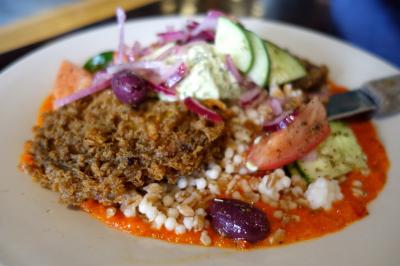 Photo of the Muse: two generous pieces of eggplant fried in falafel batter, couscous farro salad, red pepper pesto, Greek yogurt tahini and xoriatiki salad.
